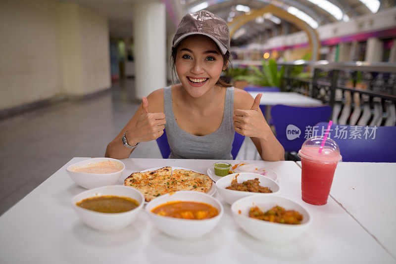 年轻美丽的亚洲女游客在餐厅享受印度美食的肖像