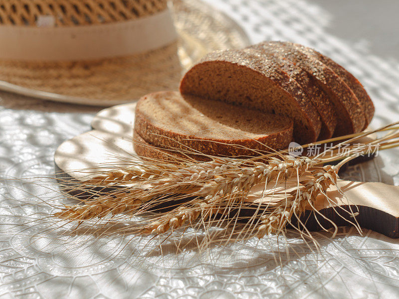 切成薄片的面包与小麦穗木砧板和模糊的草帽背景