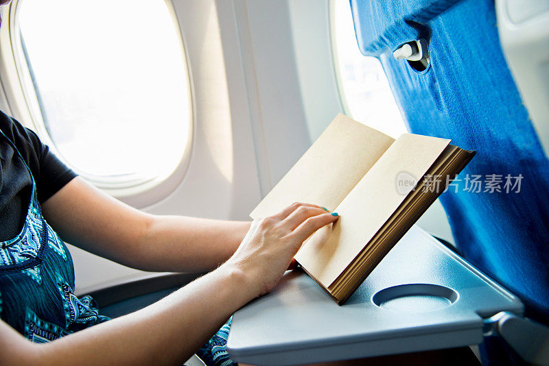 年轻女子在飞机上看书