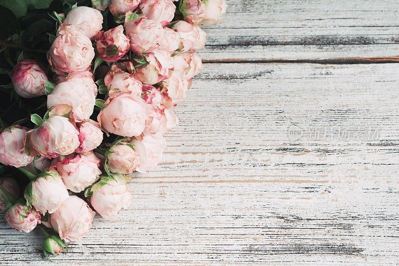粉红色的灌木玫瑰在复古的木制背景与文本复制空间。婚礼花的框架