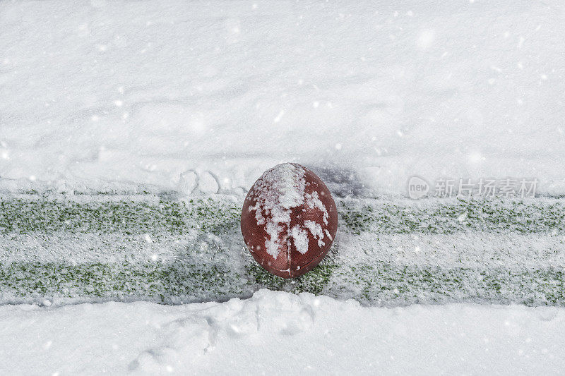 一个美式足球坐在雪地里的院子线上