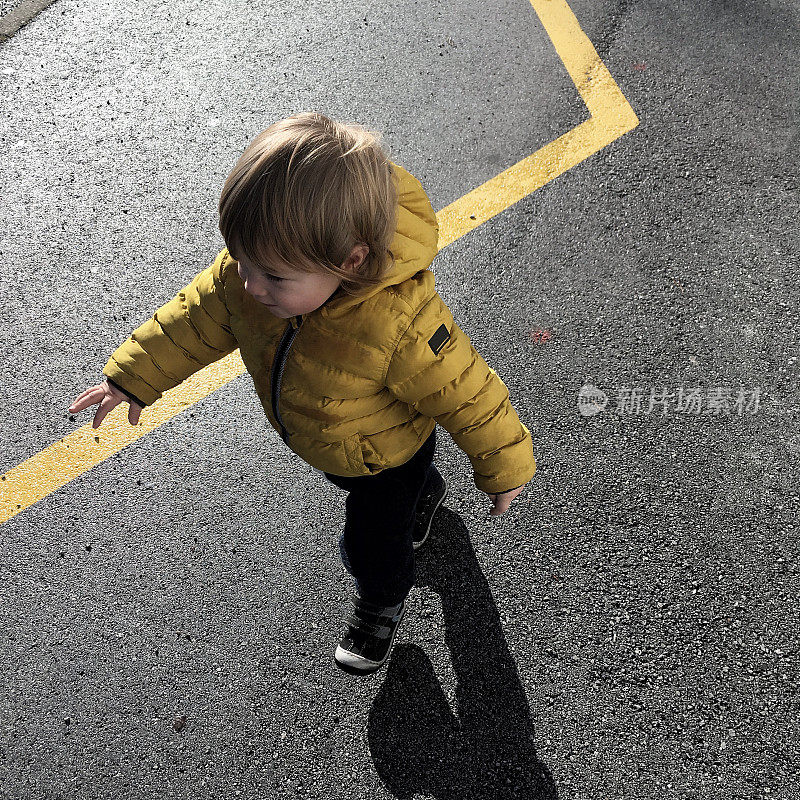 一个蹒跚学步的孩子走在街上的照片