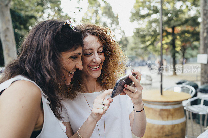 两个年轻的成年女性一起看智能手机