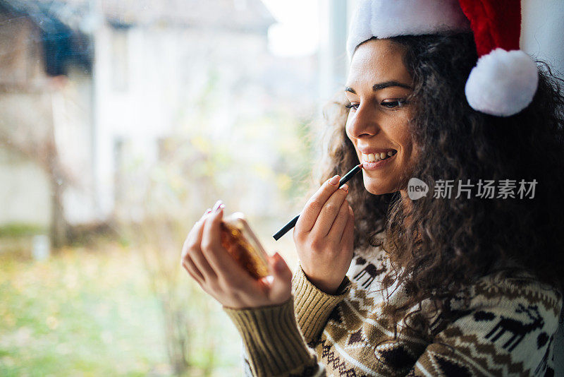 迷人的年轻女子在窗前化妆