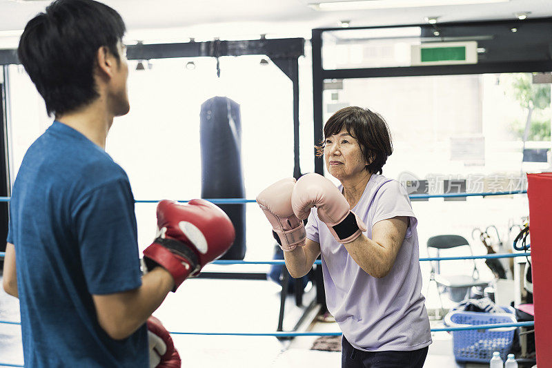 年长的成年女性在拳击馆里接受男性教练的训练