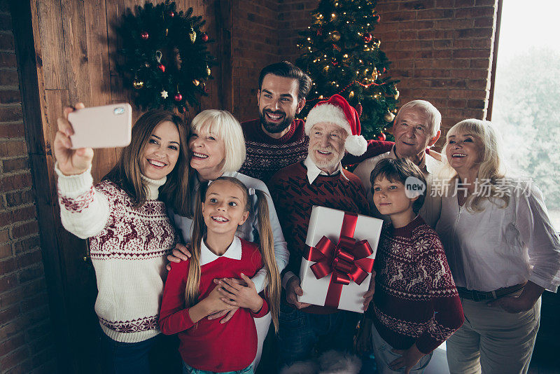 2019年12月传统圣诞。欢乐全家团聚的肖像。白发苍苍的爷爷奶奶、孙子孙女、妹妹、弟弟、儿子、女儿用手机自拍开心快乐