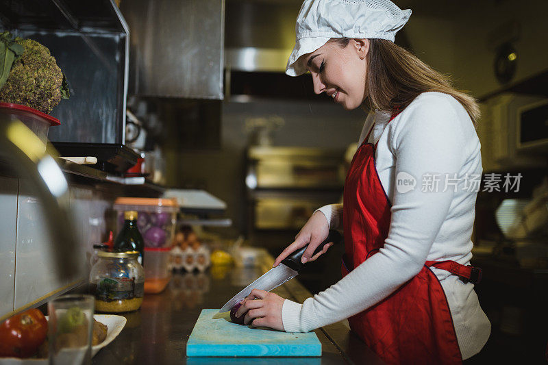 在餐厅厨房切食材的女人