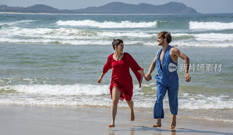 一对年轻夫妇在拜伦湾附近的海滩上散步。