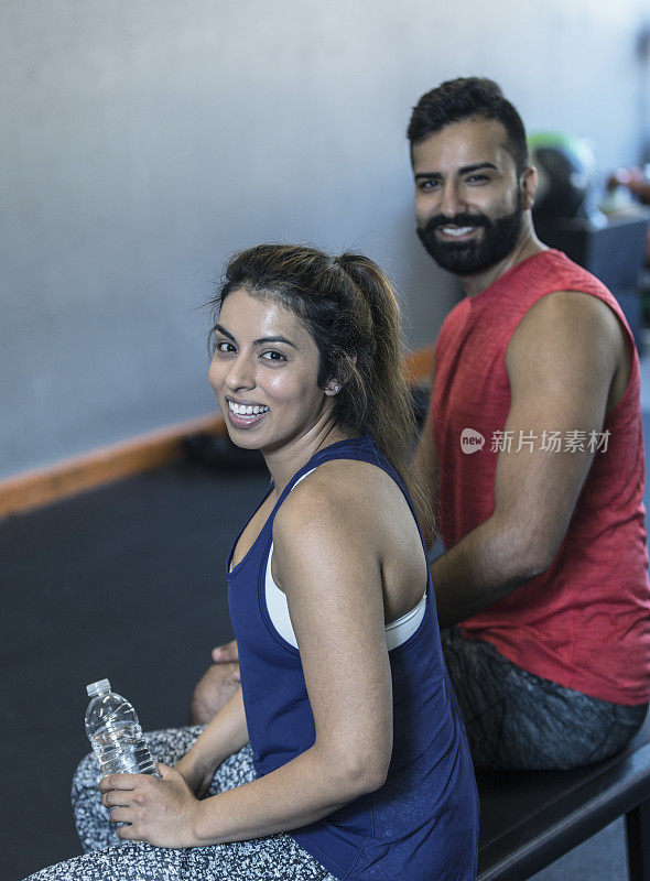 异性夫妇在交叉训练健身房喝水休息