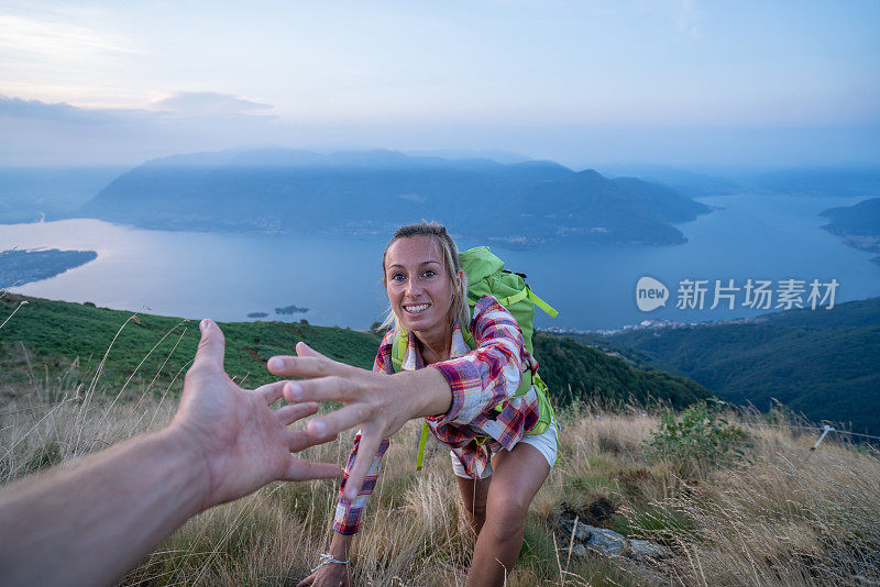 登山队员在山顶协助队友，向山顶伸出援手