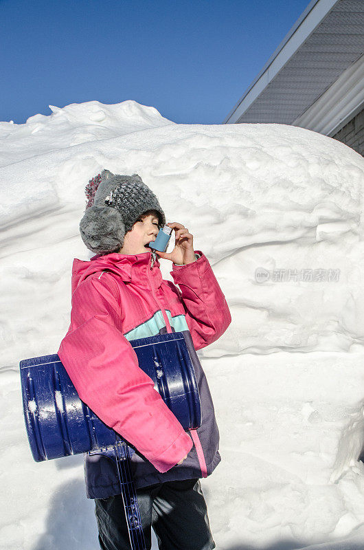 小女孩在铲雪后使用哮喘泵