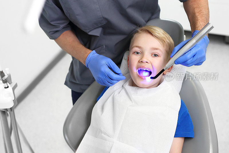 孩子在看牙医。光固化密封，一个孩子在牙科诊所