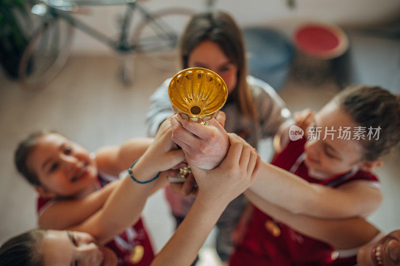 女子篮球运动员和教练一起捧着奖杯