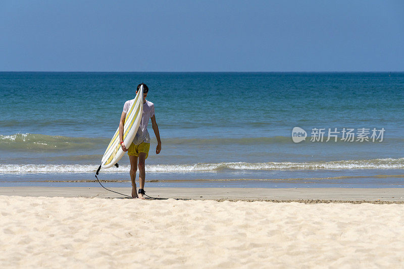 一个年轻人带着冲浪板离开帕卡朗海滩