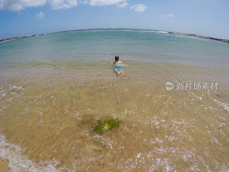 在天堂里游泳，孩子们在考艾岛的海洋里游泳，在荒芜的海滩上玩耍