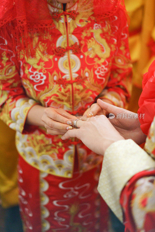 新娘身着传统服饰为新郎戴上结婚戒指