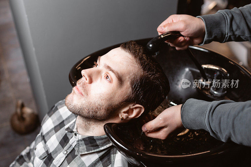 师傅在理发店里给顾客洗头，美发师为年轻人做发型。