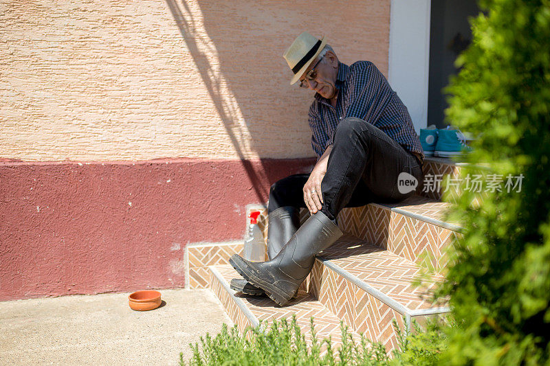一位老人，连胶靴都穿不上。