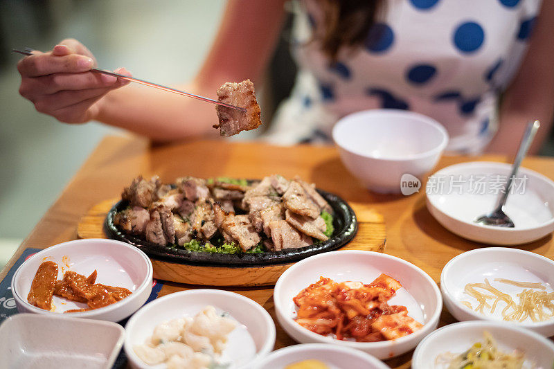 用韩国金属筷子夹着烤猪肉的女人