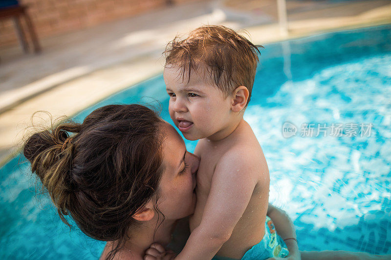 妈妈在游泳池里亲吻宝宝的肚子