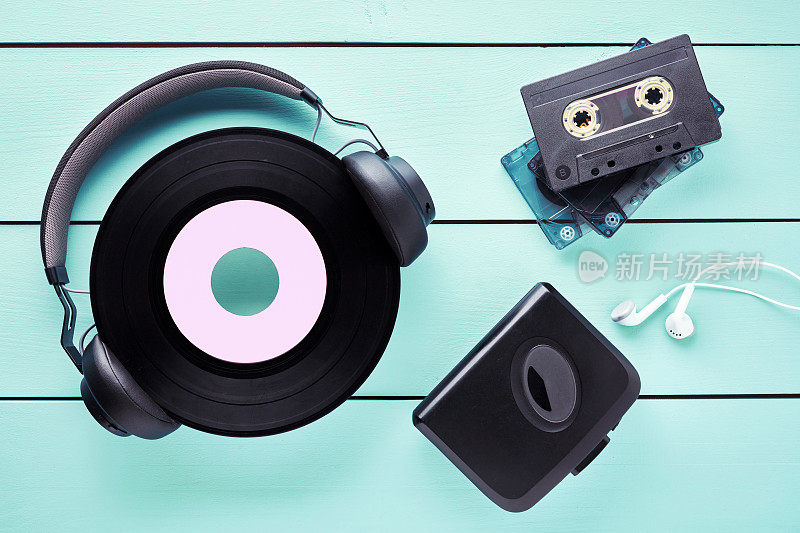 老式的黑胶唱片，耳机，耳机，卡式录音机和磁带放在木桌上