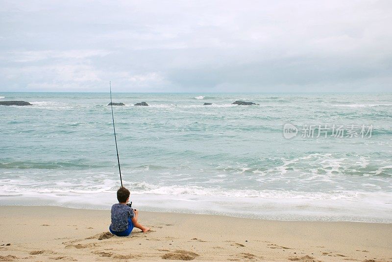 海边冲浪钓鱼的小男孩