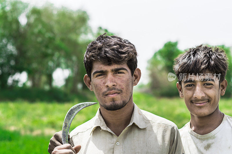 两个穿着巴基斯坦传统服装的亚洲农民站在他们的菜场旁边