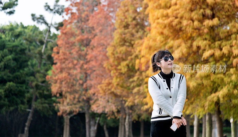 女人站在秋天的公园里