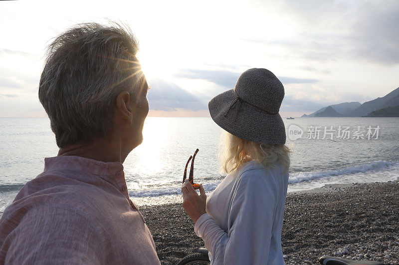 一对夫妇在日出时骑着自行车走在海滩上