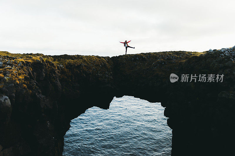 在冰岛，女人停留在美丽的拱门上看着大海