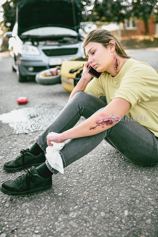 一名女性在摩托车事故后呼叫医护人员