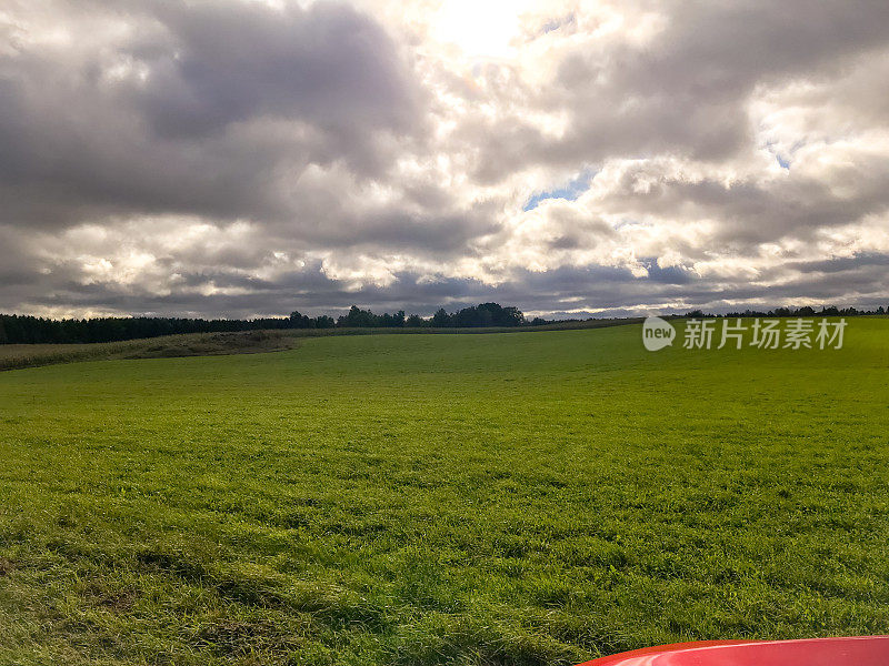 田野和部分观点的红色汽车在中西部公路旅行。