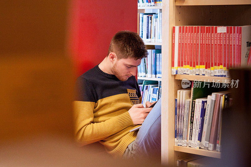 青年学生在图书馆使用手机