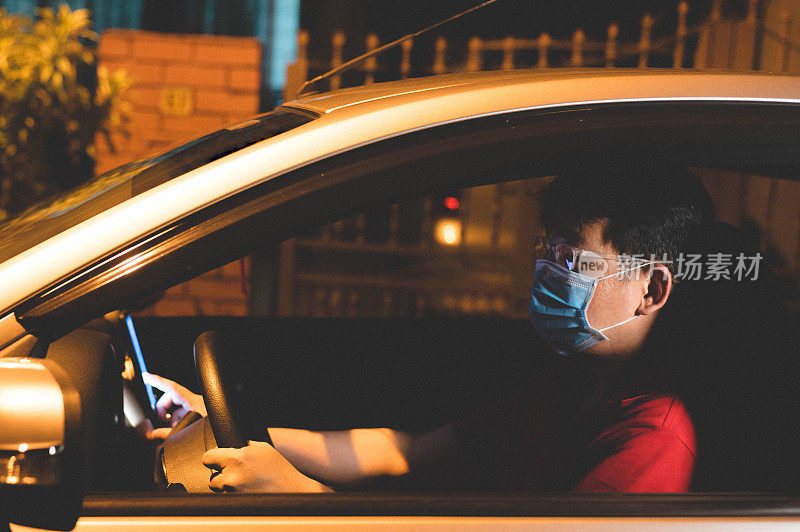 亚洲男性网约车司机戴着口罩使用智能手机