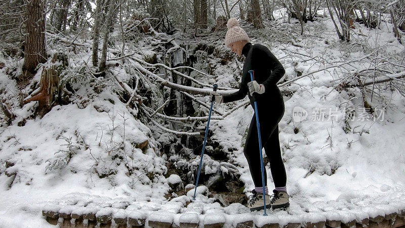 女性徒步旅行者走过被雪覆盖的木板路