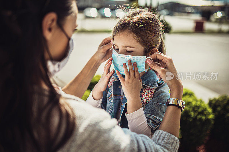 带着女儿戴着防护面具购物的女人