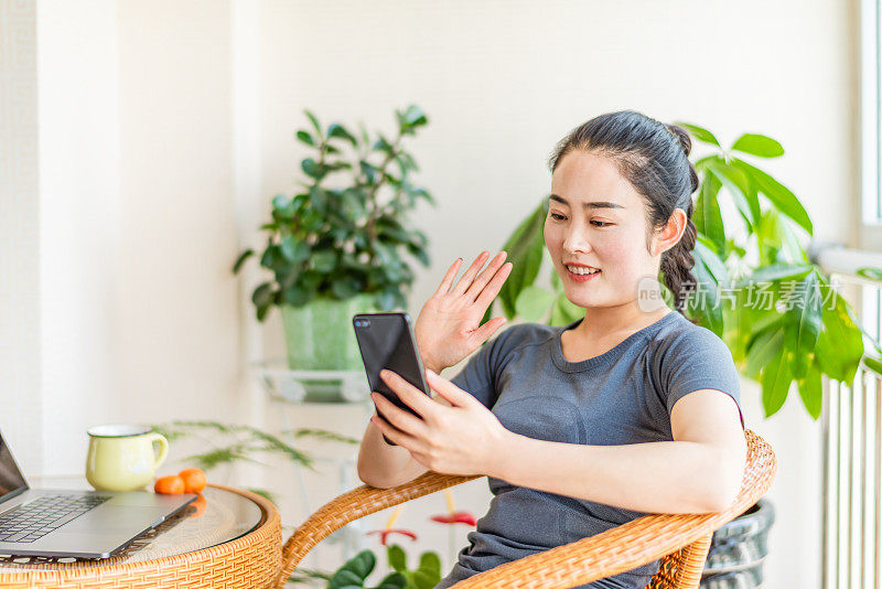 在客厅里使用智能手机的亚洲年轻女子