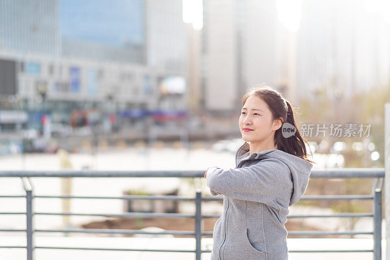 亚洲年轻女子站和伸展后，在城市跑步