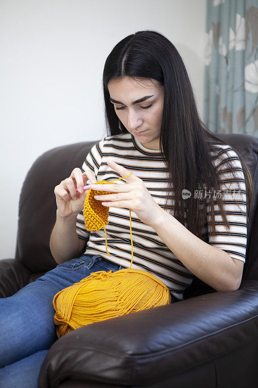 年轻女子用黄色毛线钩针编织