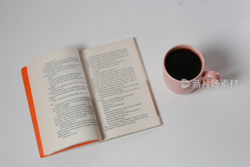 书和粉红色的咖啡杯在白色孤立的背景