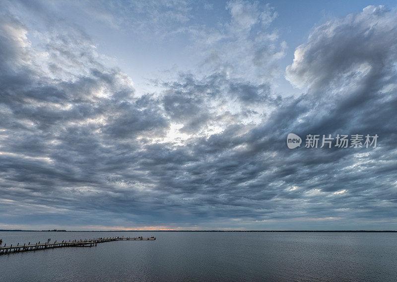 暮色的景色与剪影的人在湖边码头与雄伟的云景