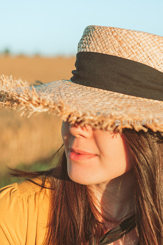 美丽的女人在田野日落草帽肖像