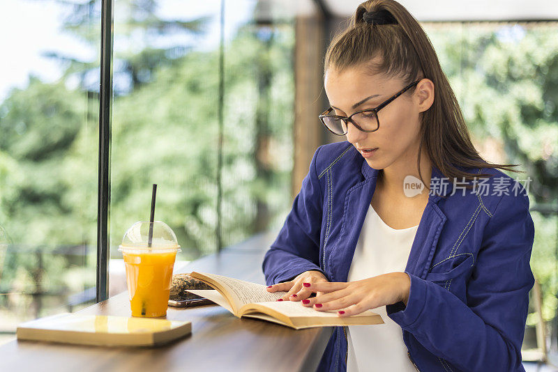 一个在快餐店里拿着书的年轻女子