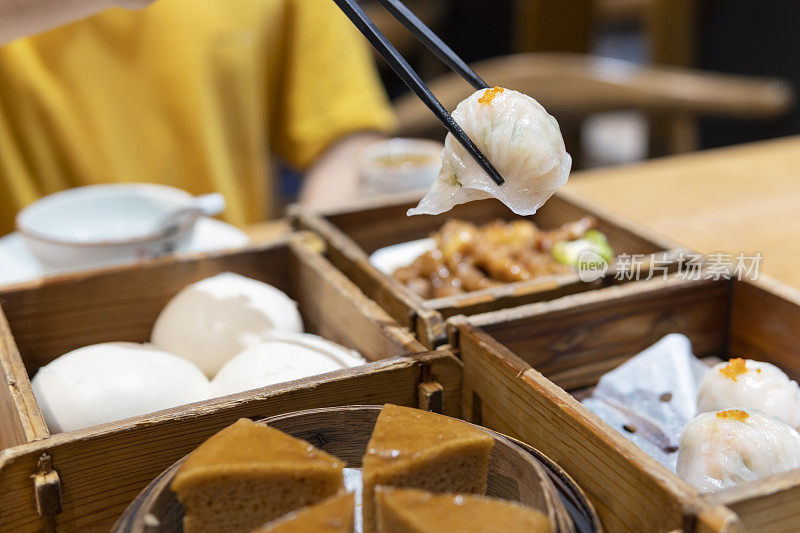 特写的一个亚洲人拿起一个广东dum叫虾饺在餐馆用筷子