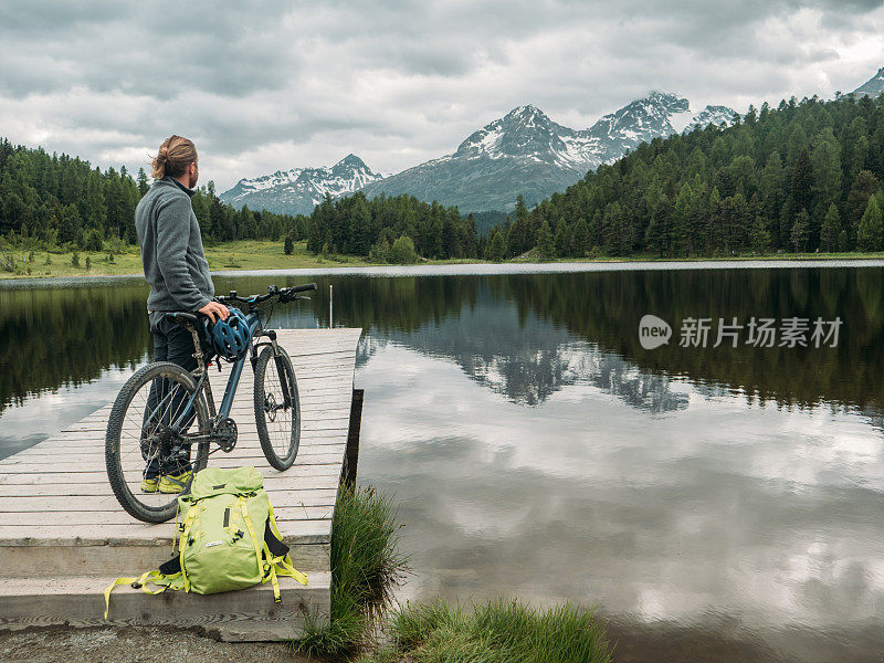 骑山地车的人在湖边看美丽的山景