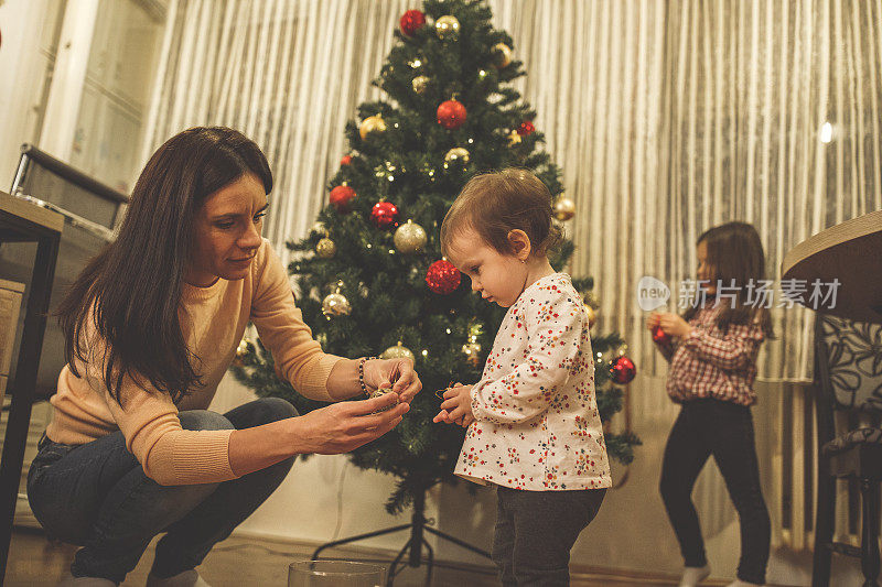 妈妈帮她的宝贝女儿装饰圣诞树