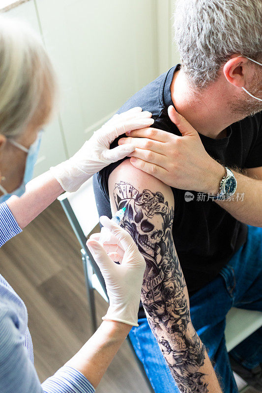 袖上纹身的男子向医生接种Covid-19疫苗