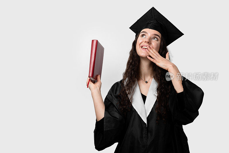 学生在毕业长袍和帽子书准备完成大学。未来的科学领袖。身着黑色长袍的年轻女院士微笑着。