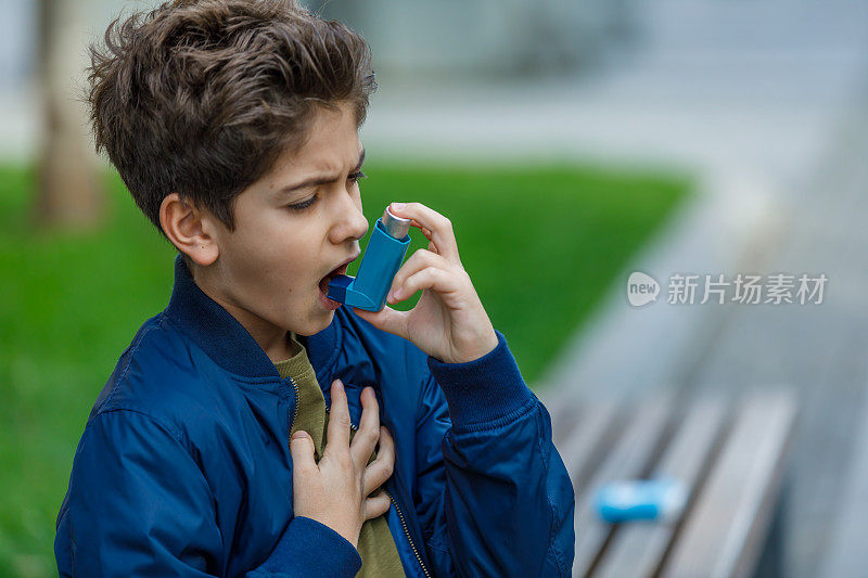 哮喘小男孩在公园里使用吸入器。