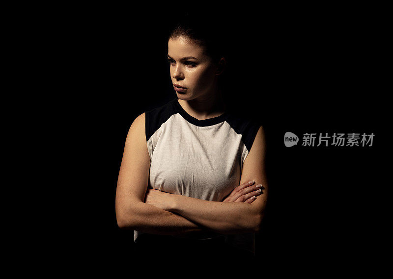 年轻的运动员在黑暗的背景-健身女人的工作室肖像